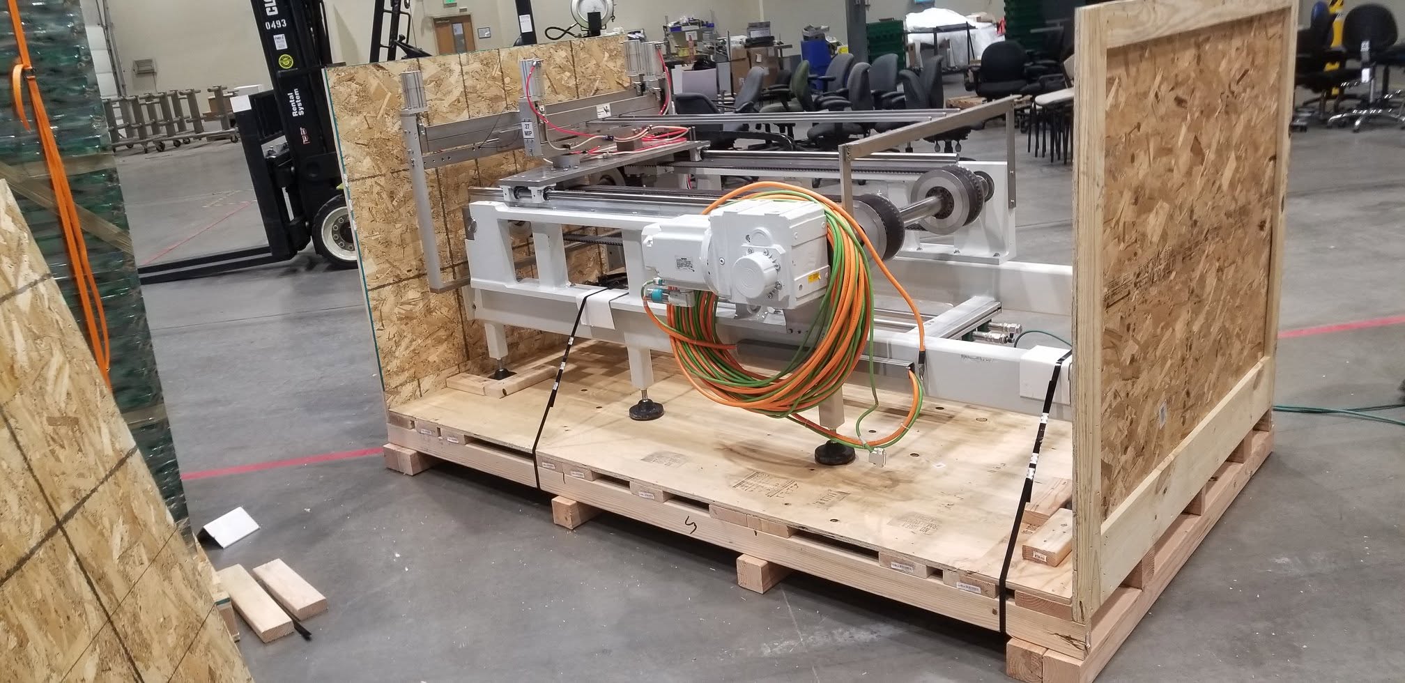 Commercial machinery secured to a custom wood skid with crate walls being installed