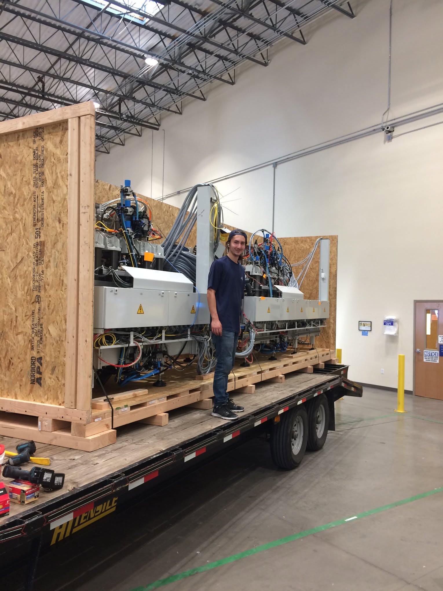 SMS technician beside large industrial machinery on a custom skid with crate walls under construction