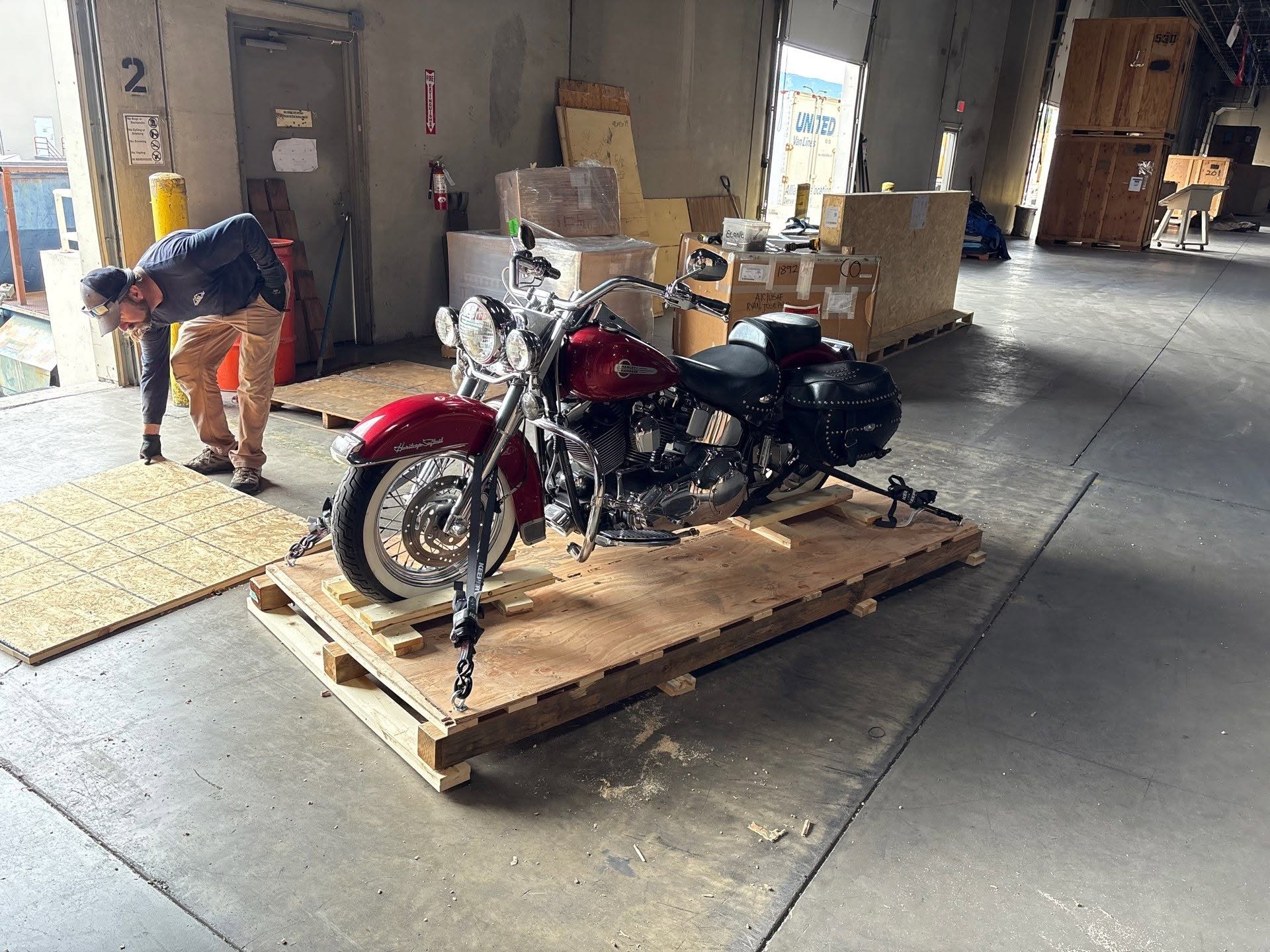 Specialized Moving Services employee securing a motorcycle to a custom wood skid before crating